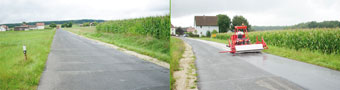 schadhafte Gemeindestraße für Einbau von Asphaltvlies mit doppelter Oberflächenbehandlung geeignet, faltenfreies Asphaltvliesverlegen mit Vliesverlegegerät